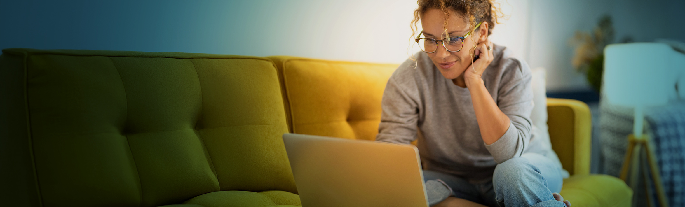 Adult working on laptop sitting on a couch.